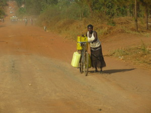 Apac.02.WomanHaulingWaterOnBike